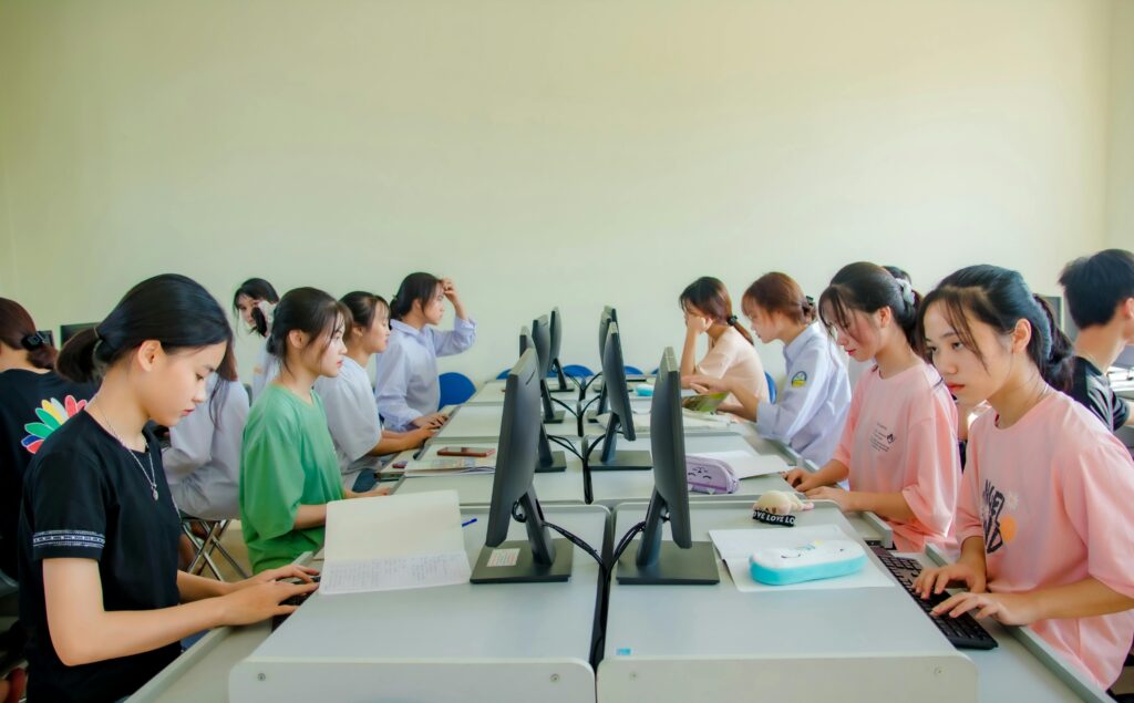 A group of students in a classroom using computers for team learning activities.